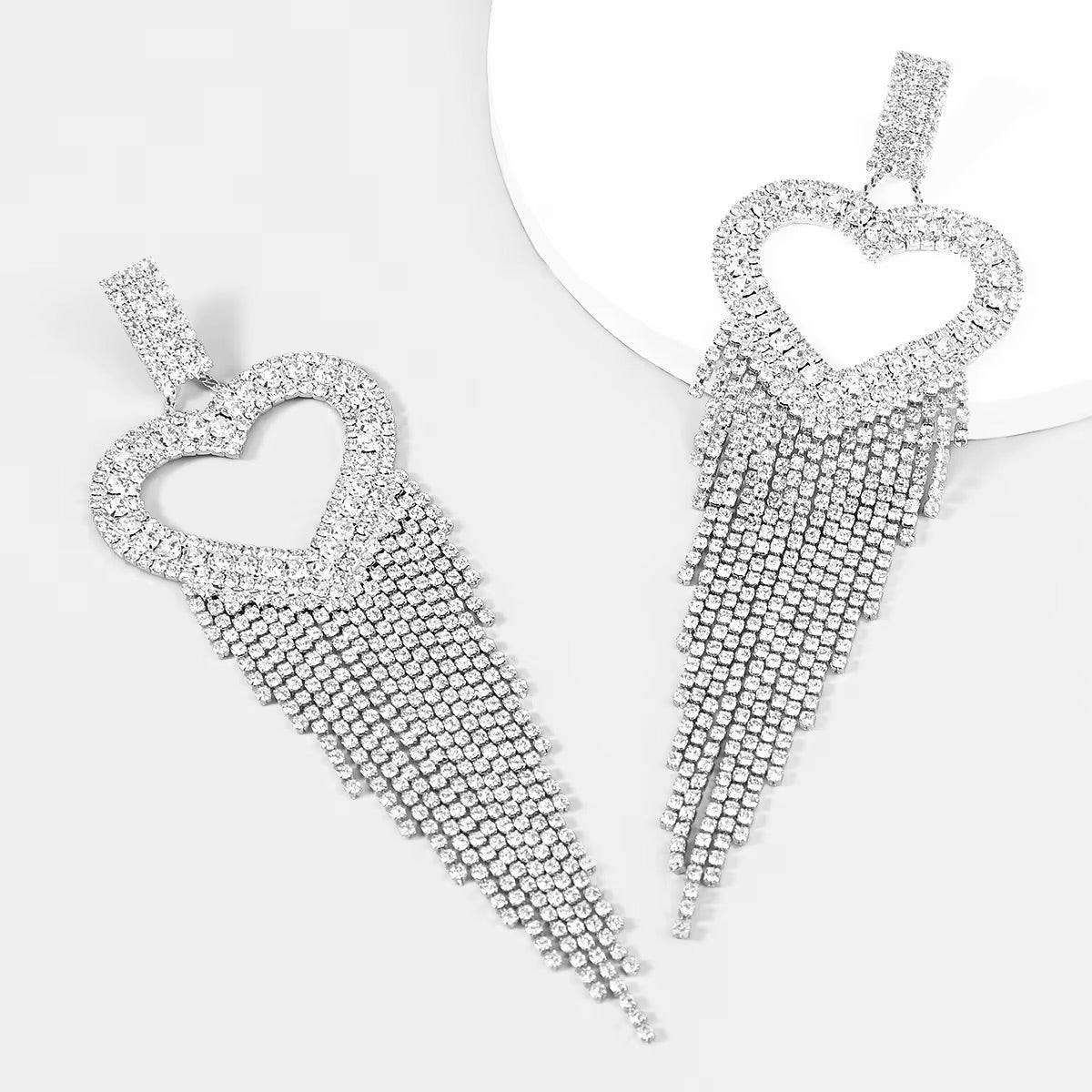Pendientes largos plateados en forma de corazón adornados con una brillante cascada de pedrería.